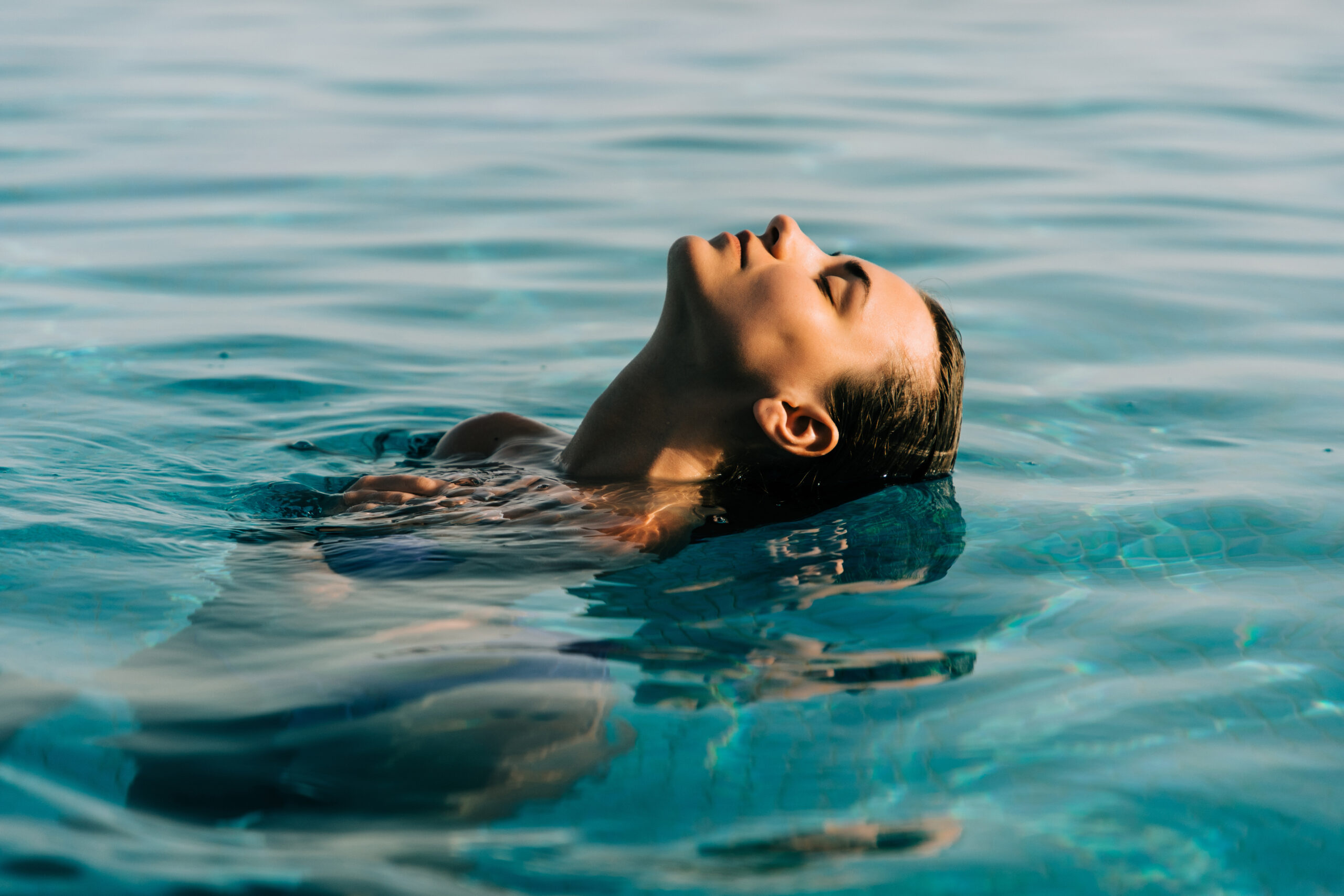 A guest floating face up in the turquoise water of the panoramic pool